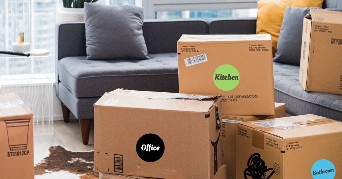 Color-coded moving boxes stacked in front of gray couch