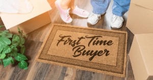 a couples feet are visible just above a doormat that says "first time buyer"